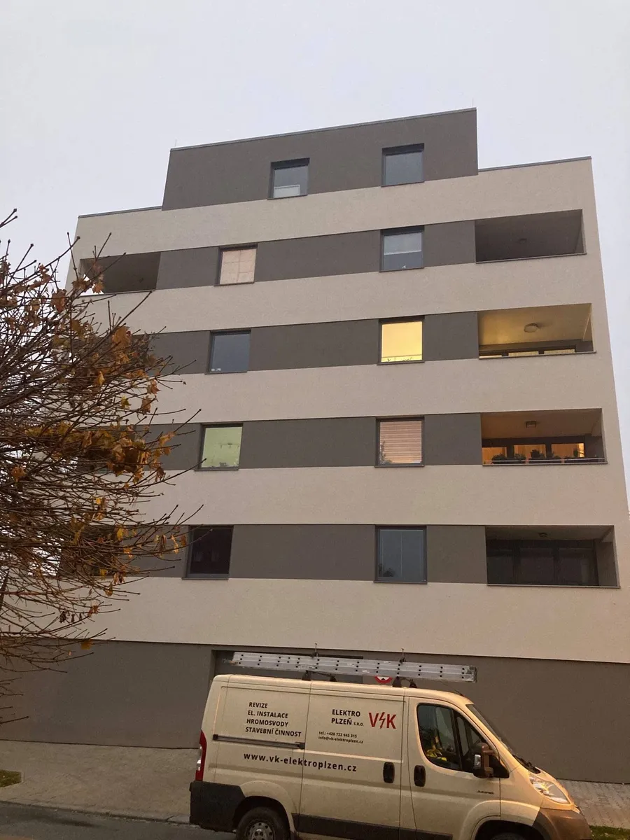 Bytový dům v&nbsp;Plzni s&nbsp;montážním vozem VK Elektro Plzeň před vchodem