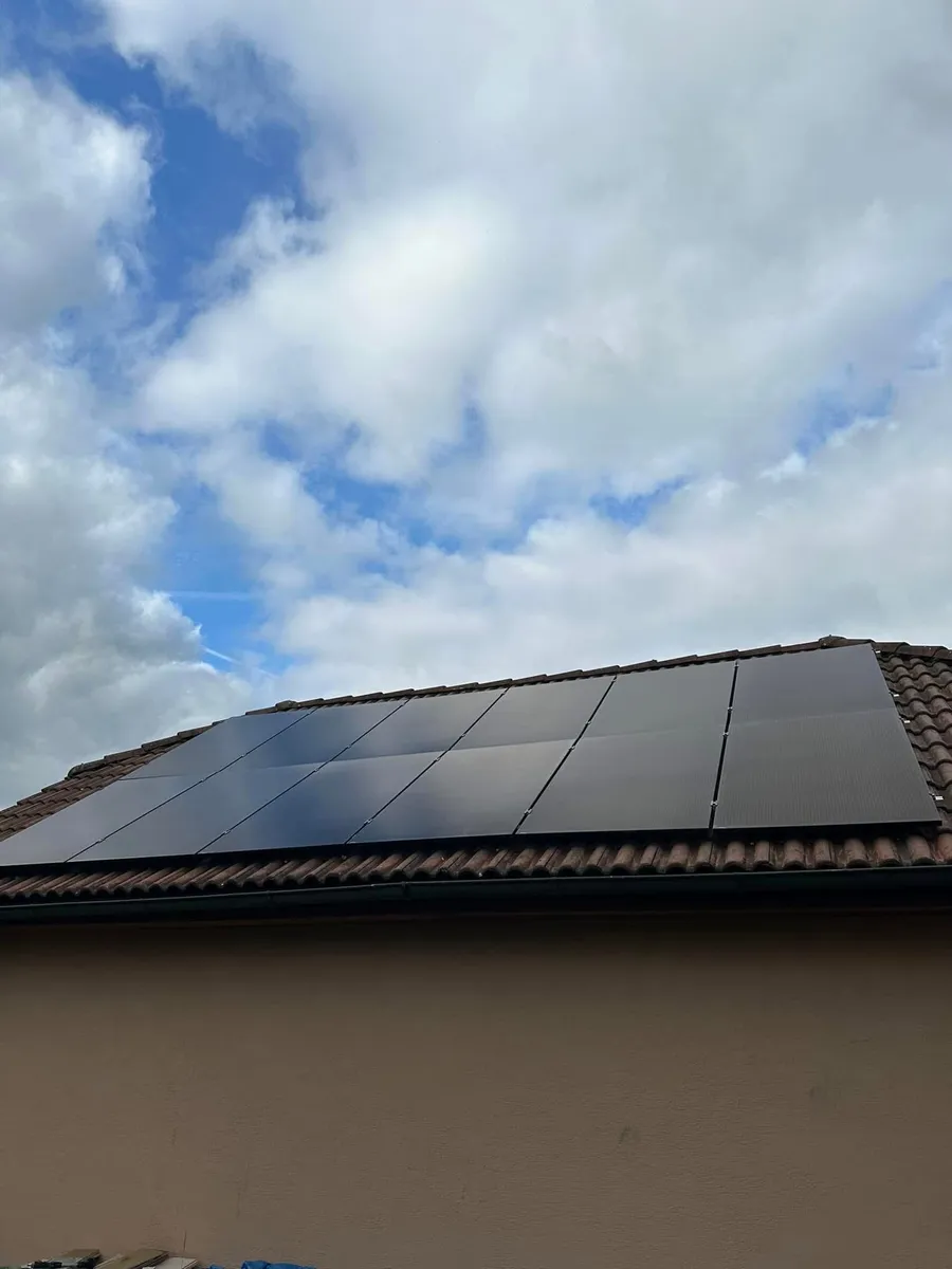 Černé fotovoltaické panely na tmavé střeše rodinného domu