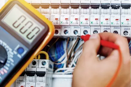 Revizní technik měří jističe v&nbsp;rozvaděči multimetrem
